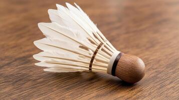 A single badminton shuttlecock rests on a wooden surface photo