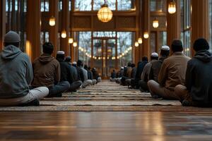 group of young Muslim men sit cross legged in mosque discussing religious teachings after performing prayers. warm lighting creates serene atmosphere enhancing their connection photo
