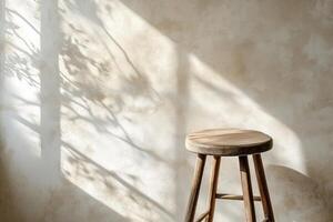 A wooden stool casts soft shadows against a textured wall, enhanced by warm, natural light. photo