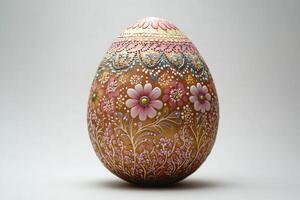 A beautifully decorated Easter egg featuring intricate floral designs in shades of pink and white on a brown background. photo