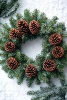 A festive holiday wreath featuring pine cones and lush evergreen branches, set against a backdrop of soft white snow. photo