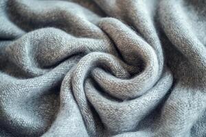A close-up of a soft, gray knitted fabric showcasing intricate textures and folds. photo
