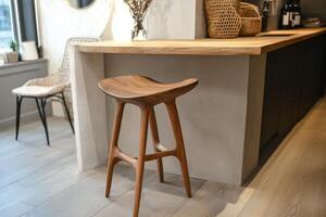 Stylish wooden stool in a modern kitchen setting with neutral tones and elegant decor. photo