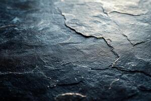 Close-up of a textured, dark stone surface with natural cracks and highlights, creating a dramatic and rugged appearance. photo