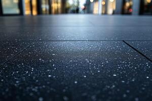A close-up view of wet, textured pavement reflecting soft ambient light in an urban setting. photo