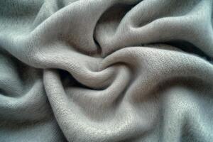 A close-up view of soft, light gray fabric elegantly draped, showcasing its gentle folds and luxurious texture. photo