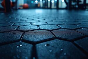 Close-up of a textured gym floor with hexagonal tiles, showcasing droplets of moisture and vibrant ambient lighting. photo