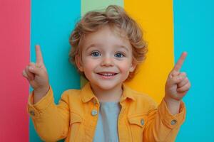 A cheerful young boy with curly hair, dressed in a yellow jacket, smiling broadly against a colorful striped backdrop. photo