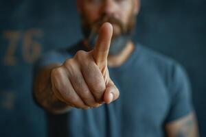 A focused man with a beard gestures with one finger raised, conveying significance and determination. photo