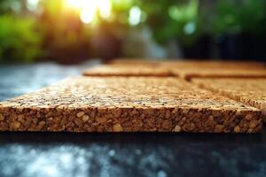Close-up of natural cork tiles on a dark surface, illuminated by warm sunlight, showcasing texture and earthy tones. photo
