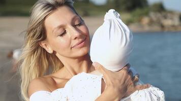 A mother hugs her little daughter while standing on the seashore. video