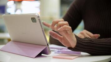 A woman uses a tablet and works while sitting at a table in a cafe. video