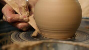 Close up hand unrecognizable man craftsman cutting excess clay pottery throwing wheel pot artist work process hobby small business potter ceramic workshop master shaping raw jug earthenware male craft video