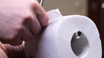 start of a new roll of toilet paper. Hand tearing toilet paper from roll in bathroom close-up video