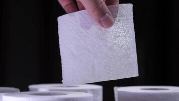 Hand holding soft toilet paper with blurred rolls in background video