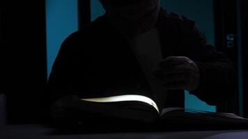 Man reading a book in the dark with light illuminating his face video