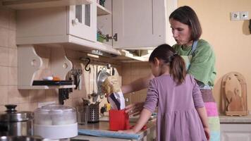 Mother and daughter pouring ingredients into container in kitchen video