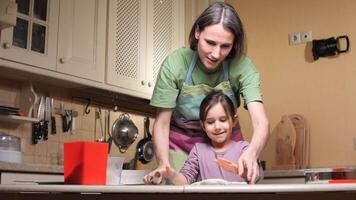 Mother and daughter making dough in kitchen using rolling pin video