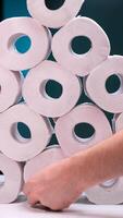 vertical A hand takes a roll of toilet paper from a large stack of toilet paper video