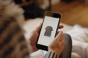 A person browsing an online shopping app for a t-shirt on smartphone photo