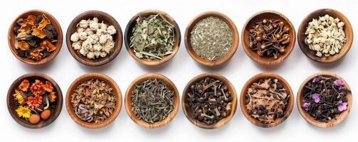 Wooden bowls filled with dried herbs, flowers, and spices arranged neatly on a white surface. photo