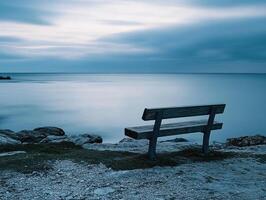 Serene coastal bench overlooking calm waters at twilight with gentle waves photo