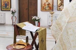 A priest is holding a book in front of a church photo