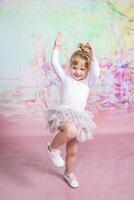 A little girl in a tutu and white shoes is dancing photo