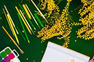 Mimosa flowers and paint brushes on green background photo