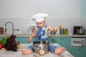 A little boy in overalls and a chef hat cooking on a counter photo