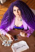 A woman with purple hair sitting at a table with some makeup photo