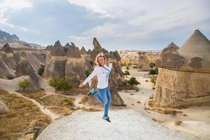 A woman jumping on a rock in front of some rock formations photo