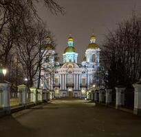 The majestic St. Nicholas Naval Cathedral in Saint Petersburg shines under night illumination, showcasing its golden domes, intricate Baroque architecture, and serene winter atmosphere photo
