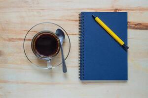 Coffee break with notebook on wooden table in office photo