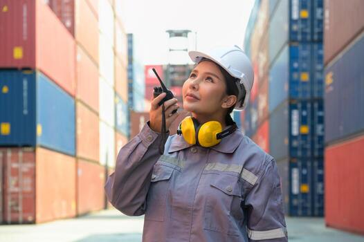 Industrial Asian female engineer checking containers using walkie talkie in front of container cargo freight ship for container loading photo