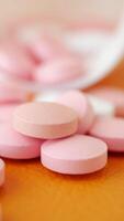 Pink tablets spilled on an orange surface in a casual setting video