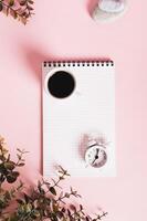 Blank notebook, cup of coffee and alarm clock on pink top view web banner photo