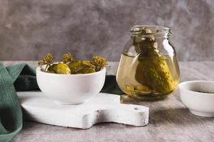 Sliced crispy pickled cucumbers in a bowl and jar on the table photo