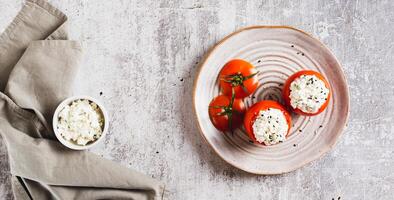 Tomatoes stuffed with cottage cheese and dill on a plate on the table top view web banner photo
