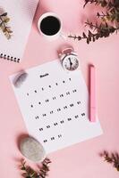 Calendar, alarm clock, notebook and pen on a pink background top and vertical view photo