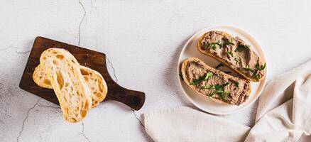 Liver pate on ciabatta on a plate on the table top view web banner photo