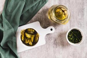 Sliced crispy pickled cucumbers in a bowl and jar on the table top view photo