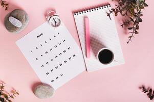 Monthly calendar and blank planning notebook on the desktop top view photo