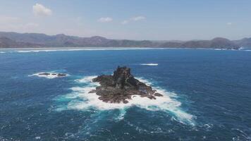 Aerial view of isolated rock island with ocean waves in Lombok, Indonesia video