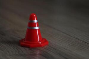 A Small Red Traffic Cone Positioned on a Wooden Surface, creating a striking visual effect photo