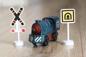 A Colorful Toy Train adorned with various Warning Signs meticulously placed on a Wooden Surface photo