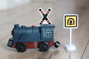 A Colorful Toy Train featuring various Warning Signs resting on a Wooden Floor surface photo