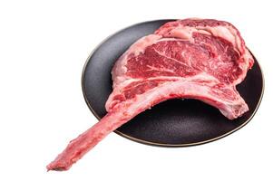 Fresh Tomahawk beef steak, raw marbled rib eye with bone on plate with herbs Isolated on a white background. top view photo