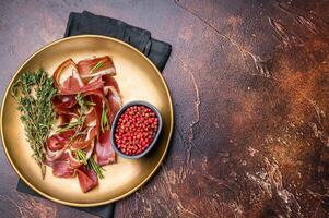 Cured duck fillet meat slices, magret smoked poultry on a plate. brown background. top view photo