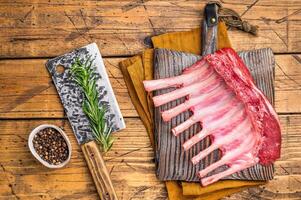 Butcher board with Raw lamb meat for chops steaks, fresh rack of mutton. wooden background. top view photo